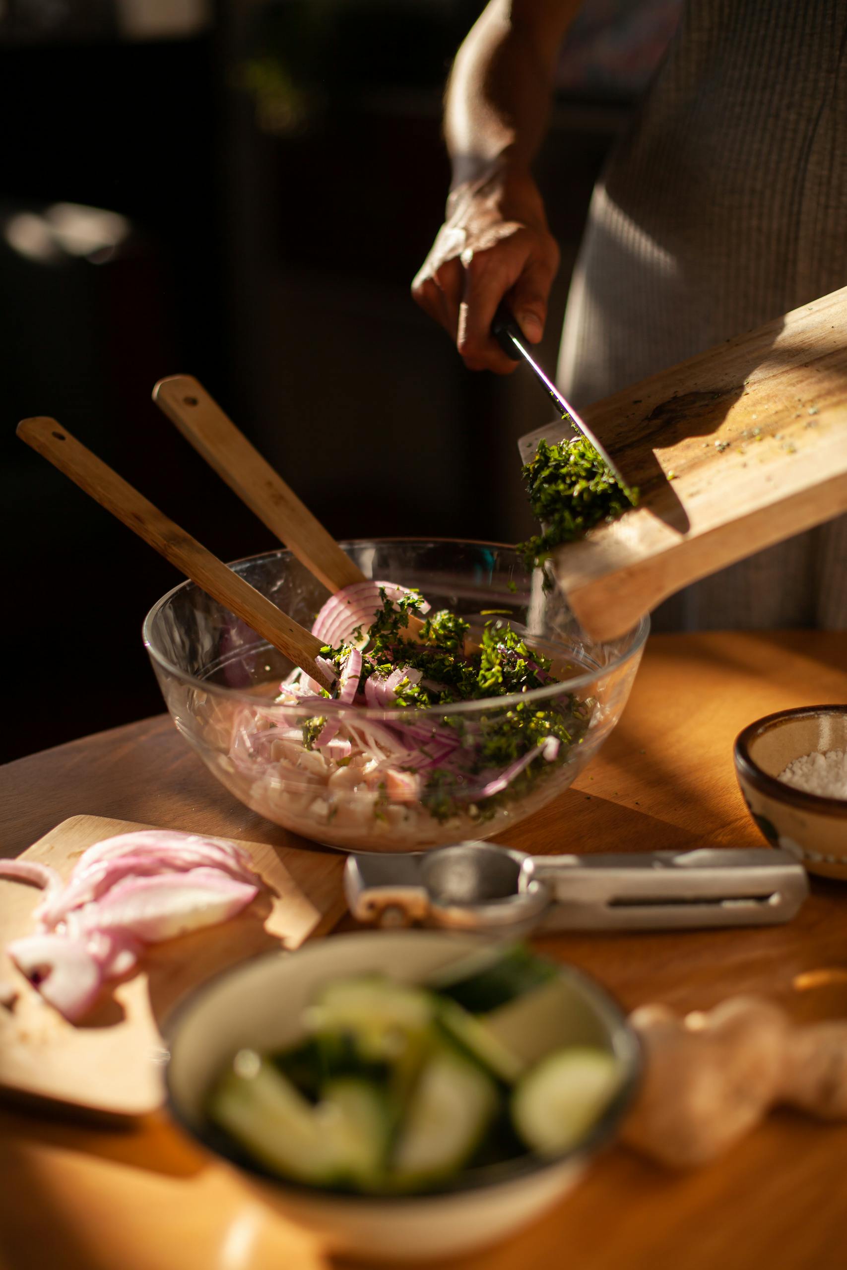 Person preparing traditional Mexican dish with fresh ingredients in a sunlit kitchen.